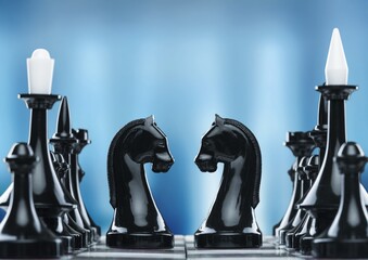 Shiny chess figures standing on wooden chessboard. Intellectual duel and tactical battle symbol....