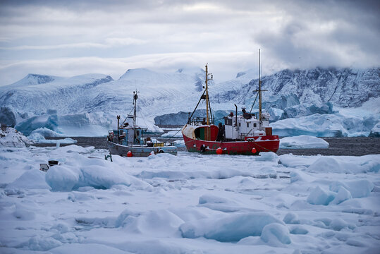 Greenland fishing boats frozen into sea ice, icebergs in winter night