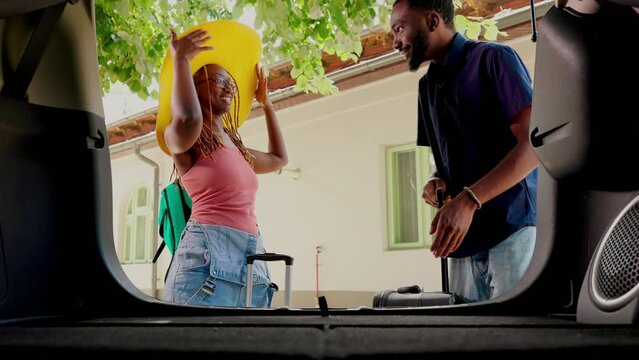 Boyfriend and girlfriend going on field trip while putting baggage inside vehicle. Happy couple loading luggage inside car trunk while going on marriage anniversary summer holiday citybreak