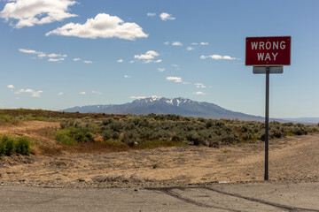 A view on the desert with mountains and sky and sign Wrong way