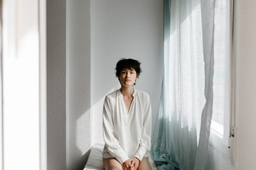 Tranquil androgynous person looking at camera in white room