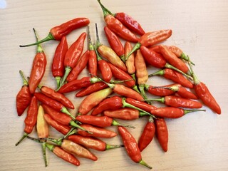 Some hot red chilies are placed on a brown wooden board