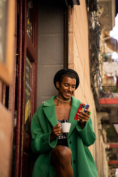 Man checking rainbow phone with coffee outside bar