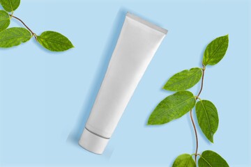 White Cream tube and branches with young small leaves. Cosmetic skincare product blank plastic package. White bottle of unbranded lotion, balsam, toothpaste mockup