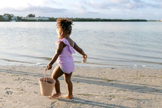 Toddler carries a beach sand bucket