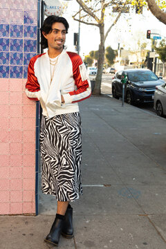 Queer Gen Z man in zebra skirt happily walking through city 