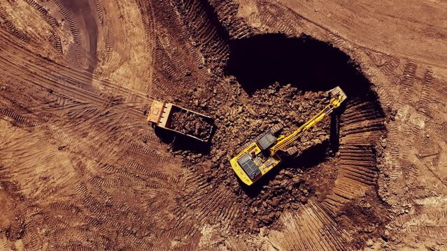 Excavator during clay mining.  mining in open pit. Aerial view of an opencast for the extraction of clay and limestone. Brick and Tile. Excavator loads clay in dump truck in quarry. 
