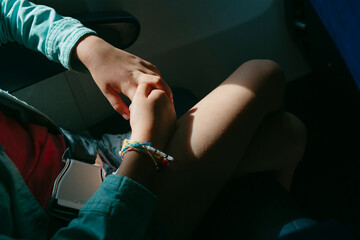 Hands and legs of young passenger on plane in sunlight with seatbelt 