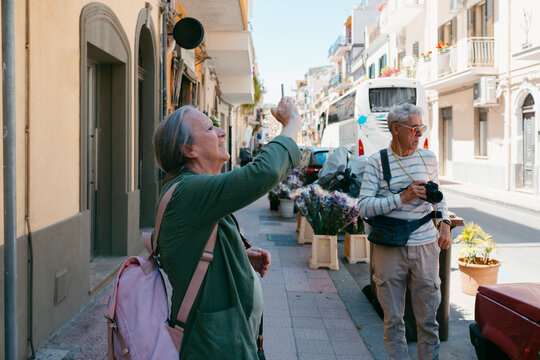 Senior tourist woman taking pictures with smartphone on a city street