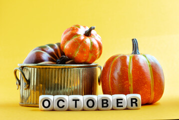 Autumn concept. On a yellow background are multi-colored pumpkins in a bowl and the inscription...