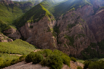 Obraz premium Breathtaking Cliff Surrounding The Valley Covered With Trees Grown Inside And On The Surface of Flat Rocky Mountain That Touches The Clouds In The Sky With Sun Rays, At Mazandaran Province, Iran.
