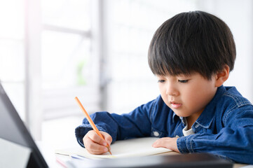 タブレットでオンライン授業をする少年　