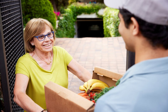 Mature woman receiving groceries from delivery man