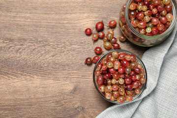 Many fresh ripe gooseberries on wooden table, flat lay. Space for text