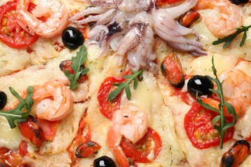 Tasty fresh pizza with seafood as background, closeup