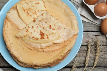 Delicious crepes and ingredients on wooden table, flat lay