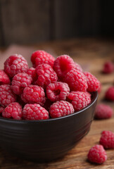 Bowl with fresh ripe raspberries on wooden table, closeup