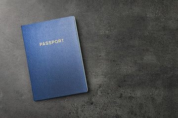 Blank blue passport on dark grey table, top view with space for text