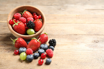 Mix of ripe berries on wooden table. Space for text