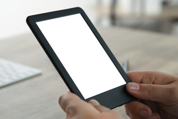 Man using e-book reader at wooden table indoors, closeup