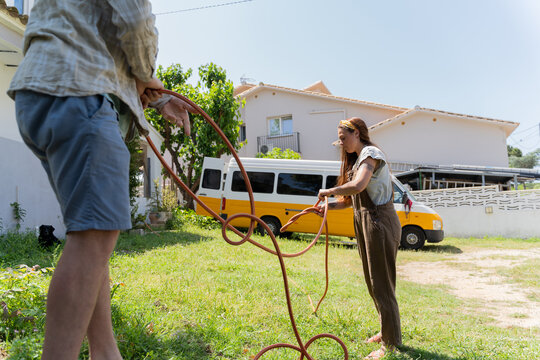 woman and man untangling water hose at garden