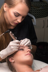 Fototapeta premium Permanent eyebrow makeup. Cosmetologist applying tattooing of eyebrows.