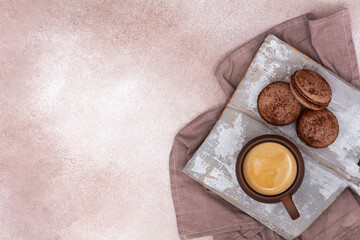 A cup of coffee and chocolate macarons on a wooden board. View from above. Breakfast concept.
