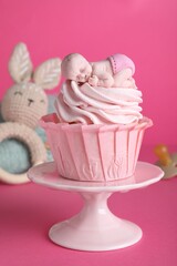 Beautifully decorated baby shower cupcake for girl with cream and topper on pink background