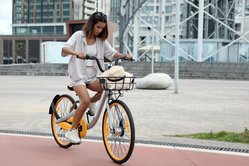 Plakat Beautiful young woman riding bicycle on lane in city. Space for text