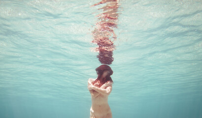 Cinematic portrait of woman holding herself underwater
