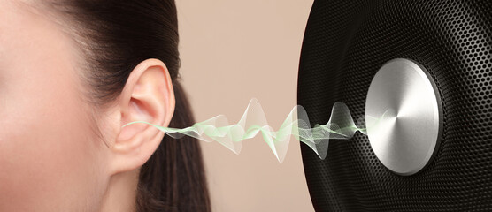 Modern audio speaker and woman listening to music on beige background, closeup view of ear. Banner...