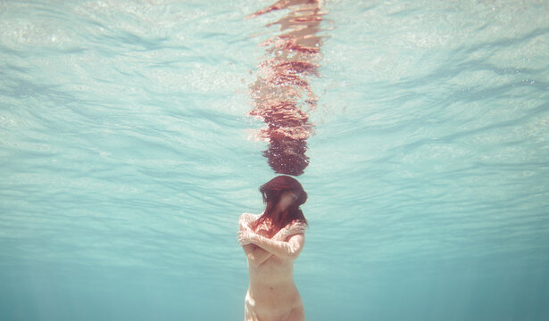 Cinematic portrait of woman holding herself underwater