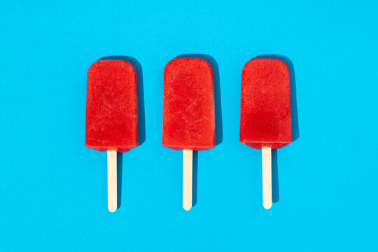 Homemade strawberry ice cream popsicles on blue background
