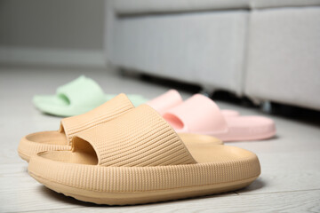 Stylish rubber slippers on floor in room, closeup