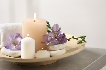 Fototapeta na wymiar Beautiful composition with spa stones and burning candles on grey table