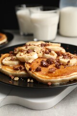 Tasty pancakes with sliced banana served on light grey table, closeup