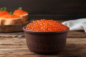 Bowl with delicious red caviar on wooden table