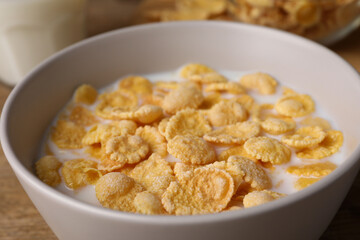 Tasty cornflakes with milk in bowl on table, closeup