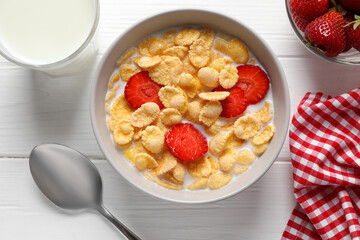 Corn flakes with strawberries in bowl served on white wooden table, flat lay