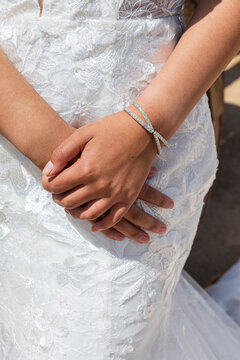 A woman hands with a bracelet and wedding dress