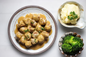 Swedish Meatball with brown mushroom sauce. Served on ceramic plate, on white table.