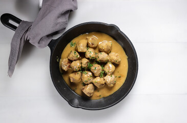 Swedish Meatball with brown mushroom sauce. Served on ceramic plate, on white table.
