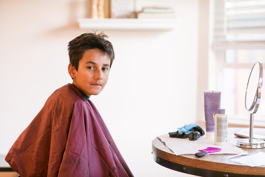 Preteen boy wearing salon cape at hairdresser