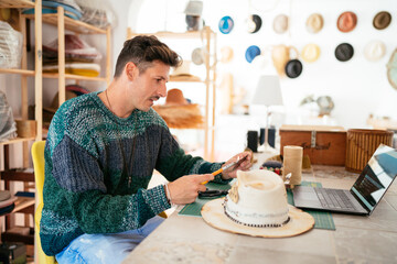 Skilled hat maker burning leather piece with torch