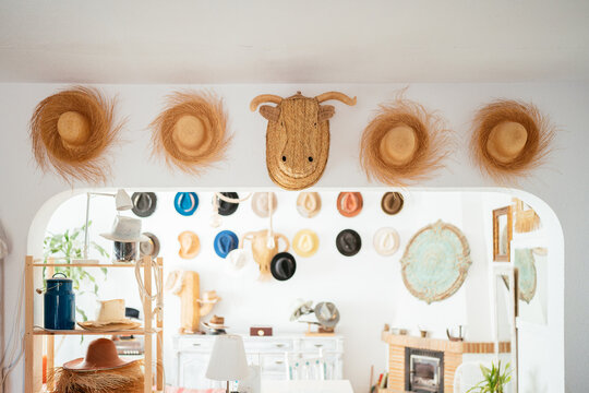 Collection of stylish handmade hats hanging on walls