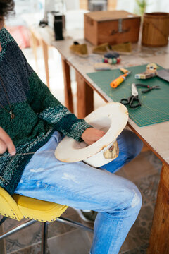 Anonymous craftsman creating woolen hat at workbench