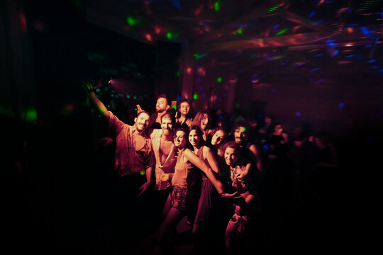 Happy friends posing for camera at night club