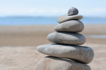 Fototapeta na wymiar Stack of stones on beautiful sandy beach near sea, closeup. Space for text