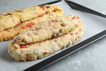 Baking tray with raw homemade Stollens on grey marble table, closeup. Traditional German Christmas bread