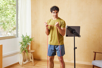 Male athlete doing biceps exercise with resistance band